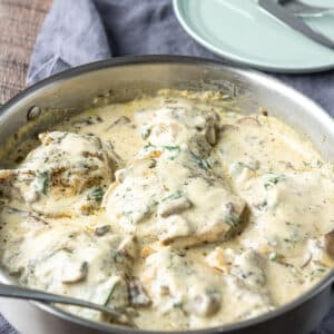 A square photo of a metal pan with a creamy sauce on chicken