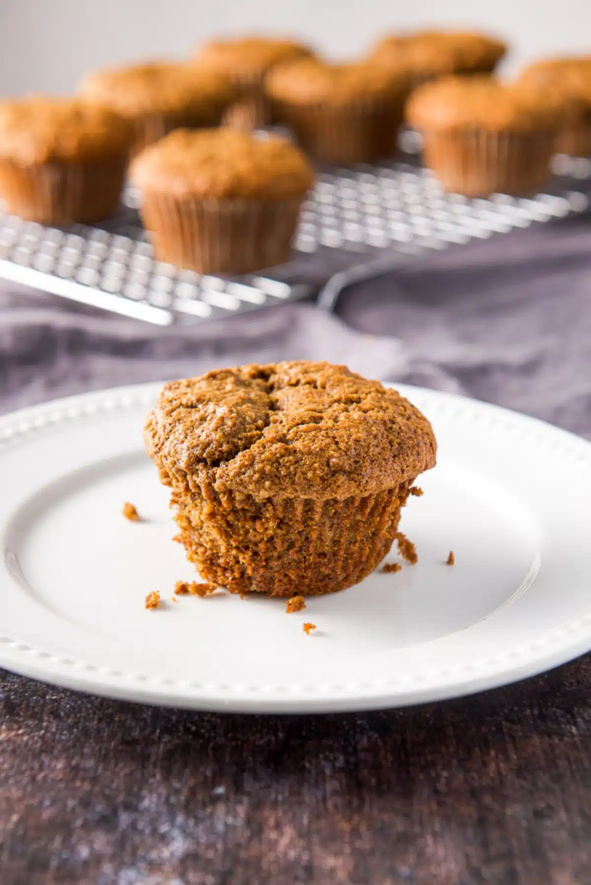 Close up of one of the oat bran muffins on a white plate with more muffins in the background