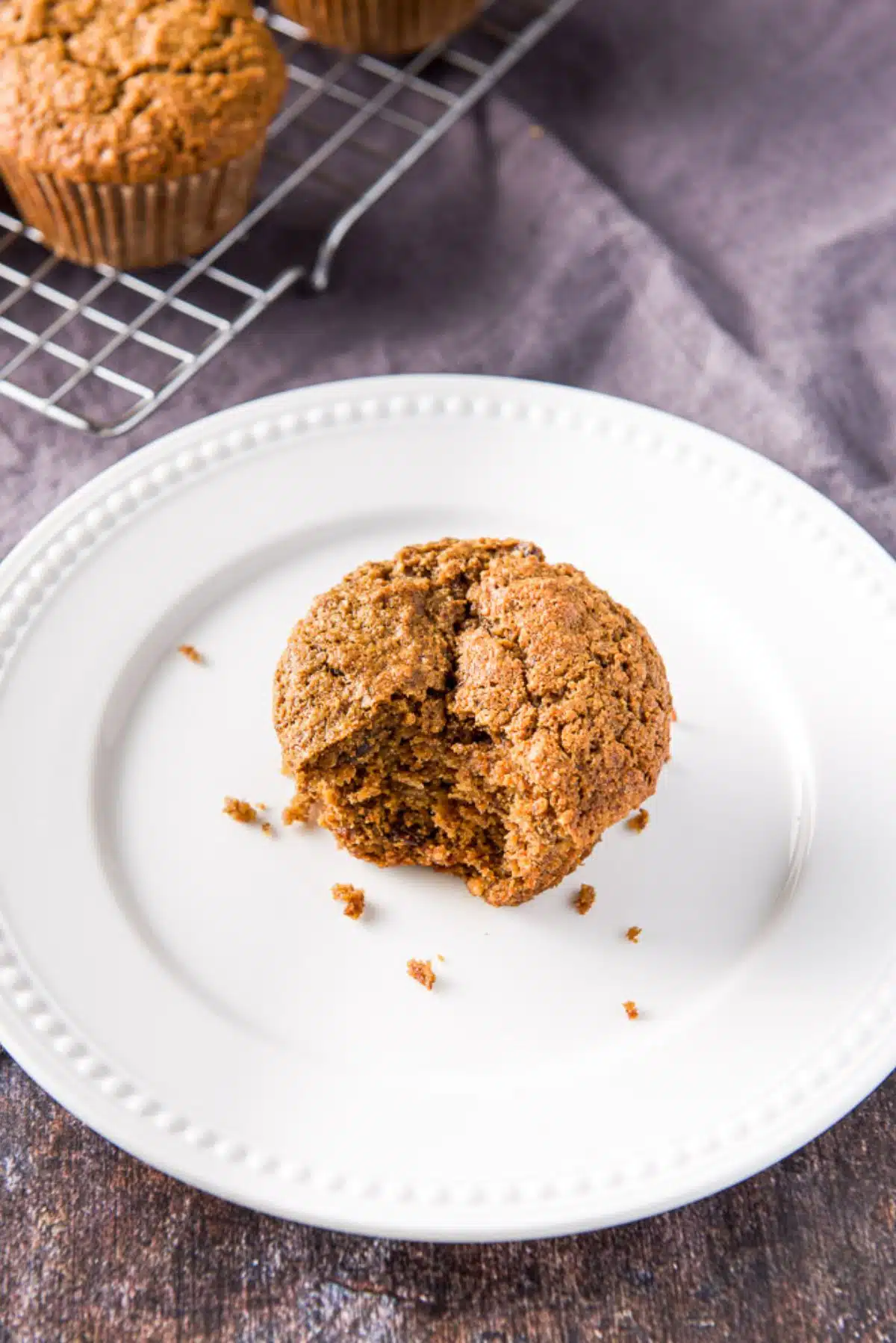 A white beaded plate with a muffin with a bite in it