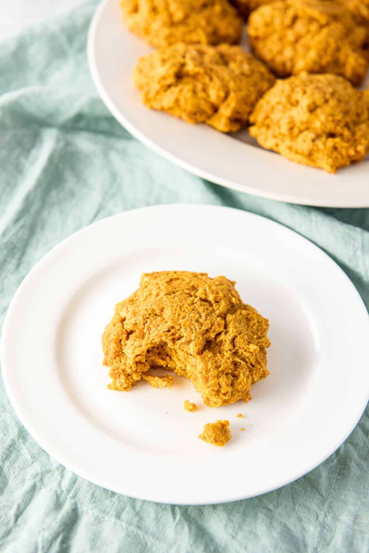 One of the potato biscuits on a plate with a bite taken out of it with more biscuits in the background