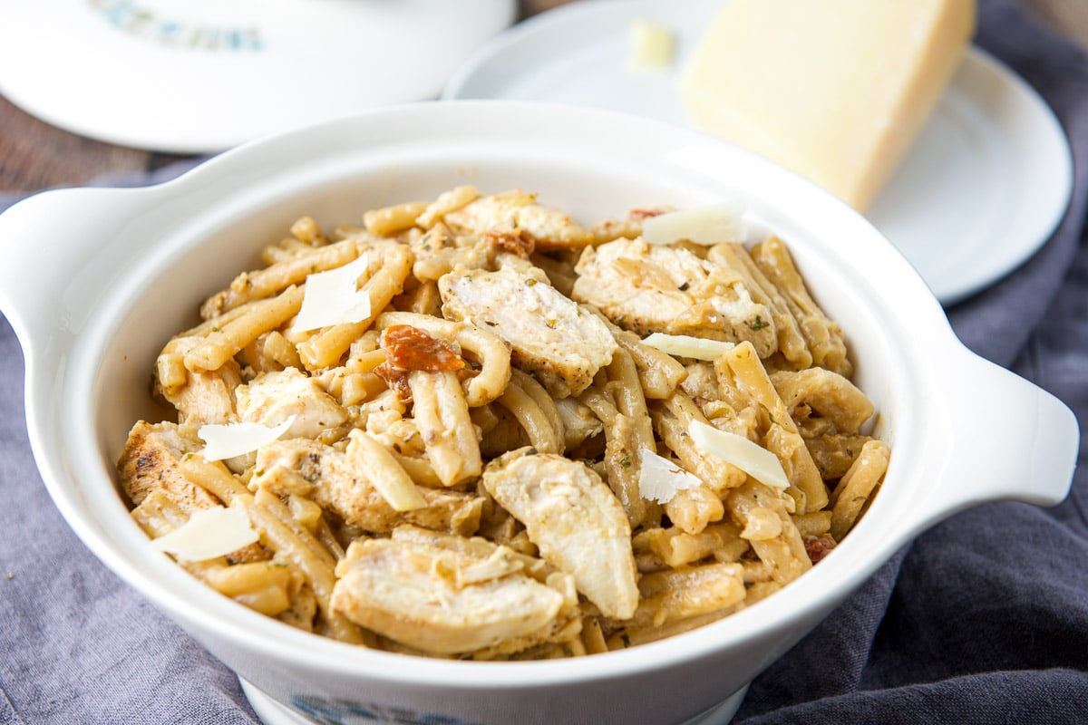 Horizontal photo of a white serving dish with the pasta and chicken with parmesan in the back