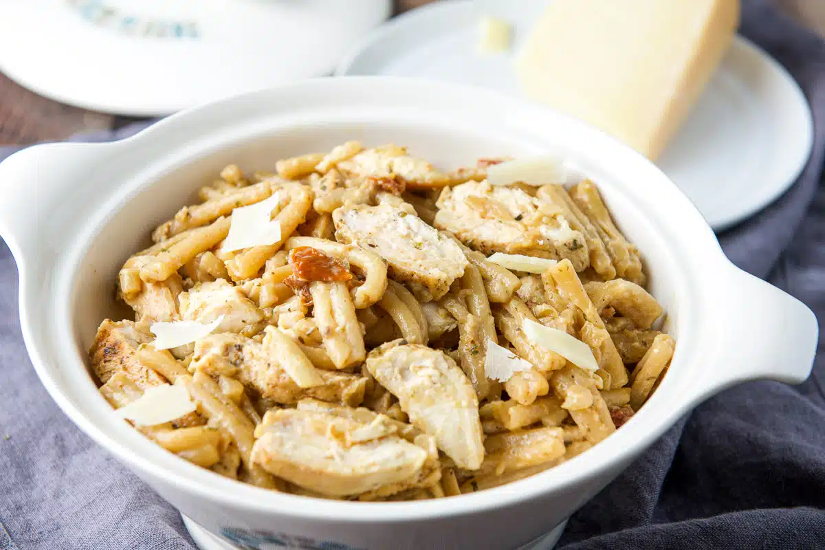 Horizontal photo of a white serving dish with the pasta and chicken with parmesan in the back
