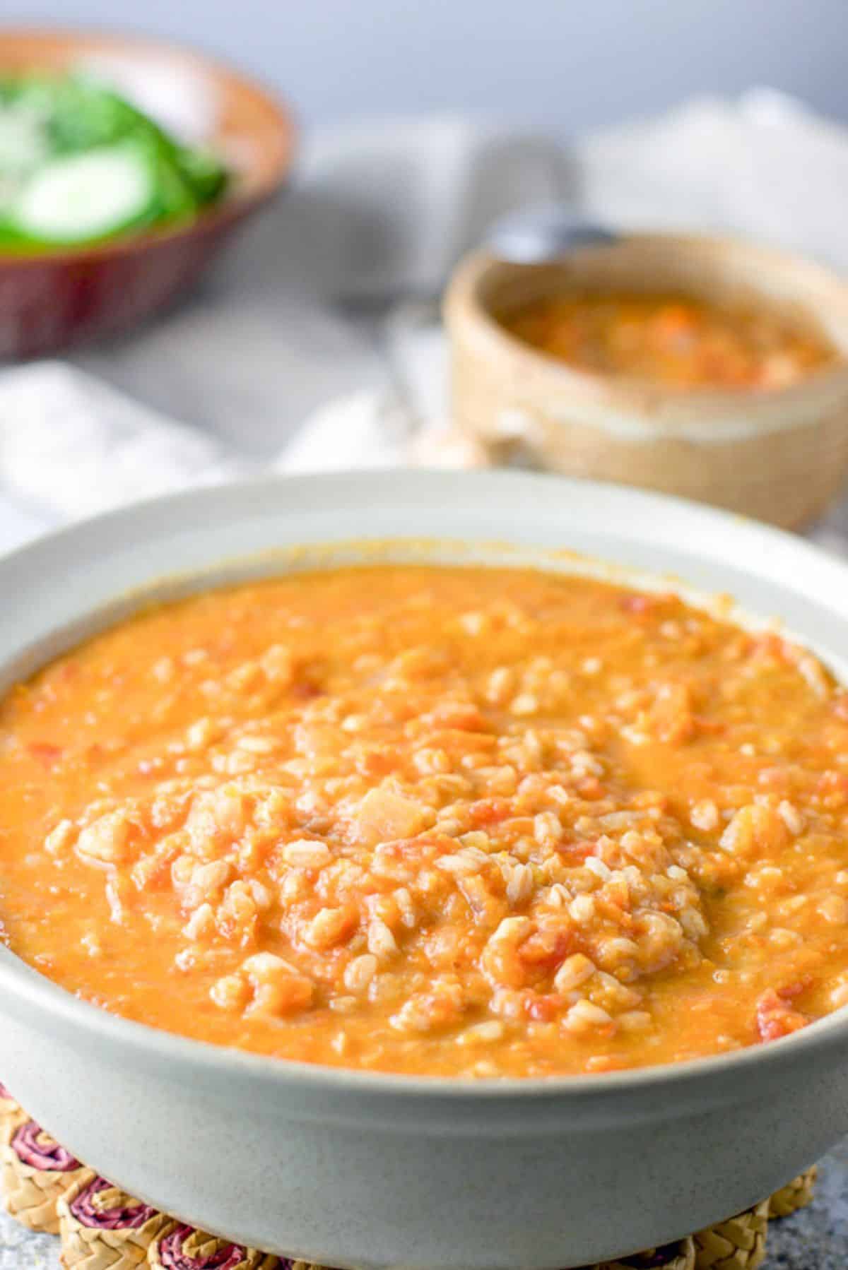 Farro cooked and the Tuscan white bean soup is in a serving bowl. There is a crock of soup and a salad behind it