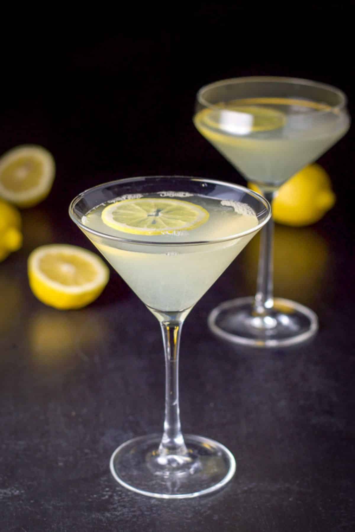 Lemon wheels floating in two martini glasses filled with the lemon cocktail