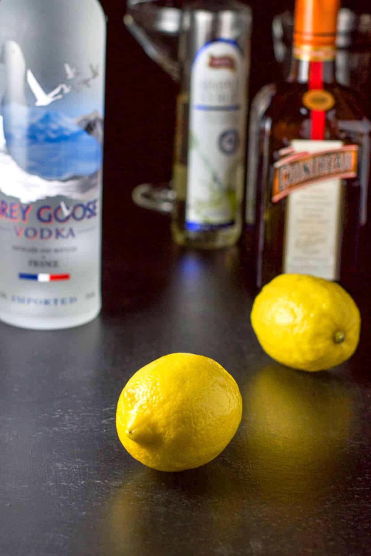 Lemon, vodka, Cointreau and simple syrup and the glassware and shaker in the background