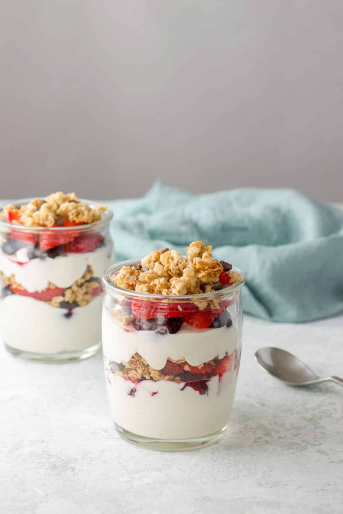 Two glasses of layered yogurt with berries and granola on the table