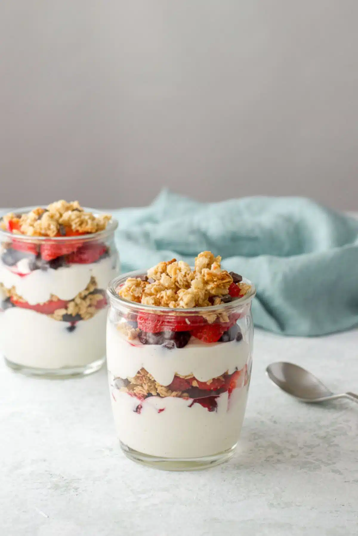 Two glasses of layered yogurt with berries and granola on the table