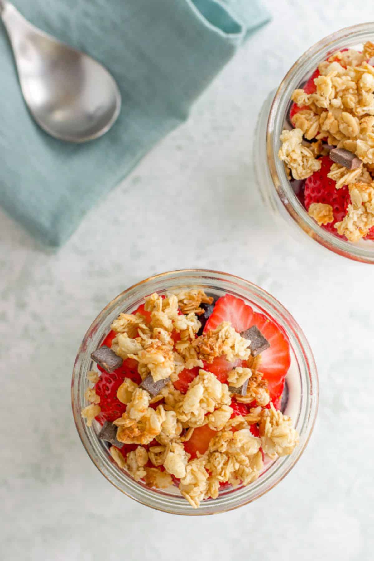 Overhead view of the granola and strawberries on the parfait, with a spoon and napkin