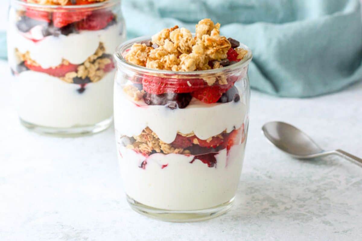 Two glass jars with layered yogurt, fruit, and granola - horizontal