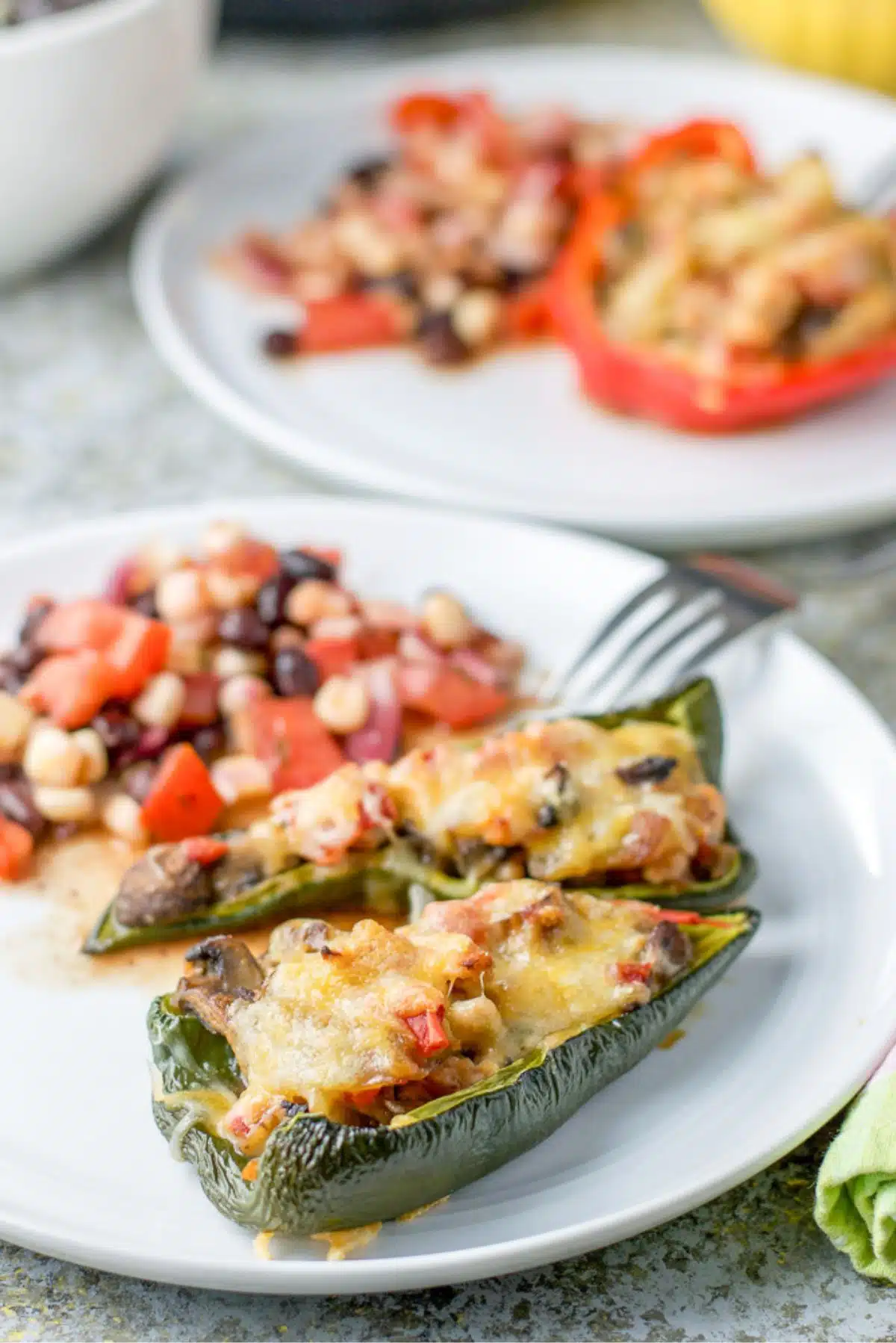 closeup of the stuffed peppers and bean salad on a plate with more ingredients in the background