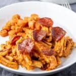 A white plate with the creamy pasta with pepperoni on top