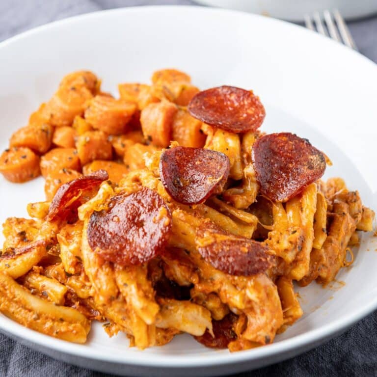 A white plate with the creamy pasta with pepperoni on top