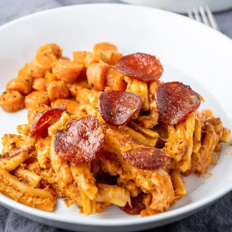 A white plate with the creamy pasta with pepperoni on top