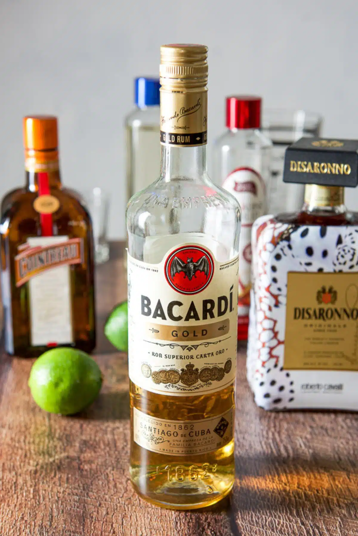 Rums, almond liquor, Cointreau, limes, simple syrup, and grenadine on a table