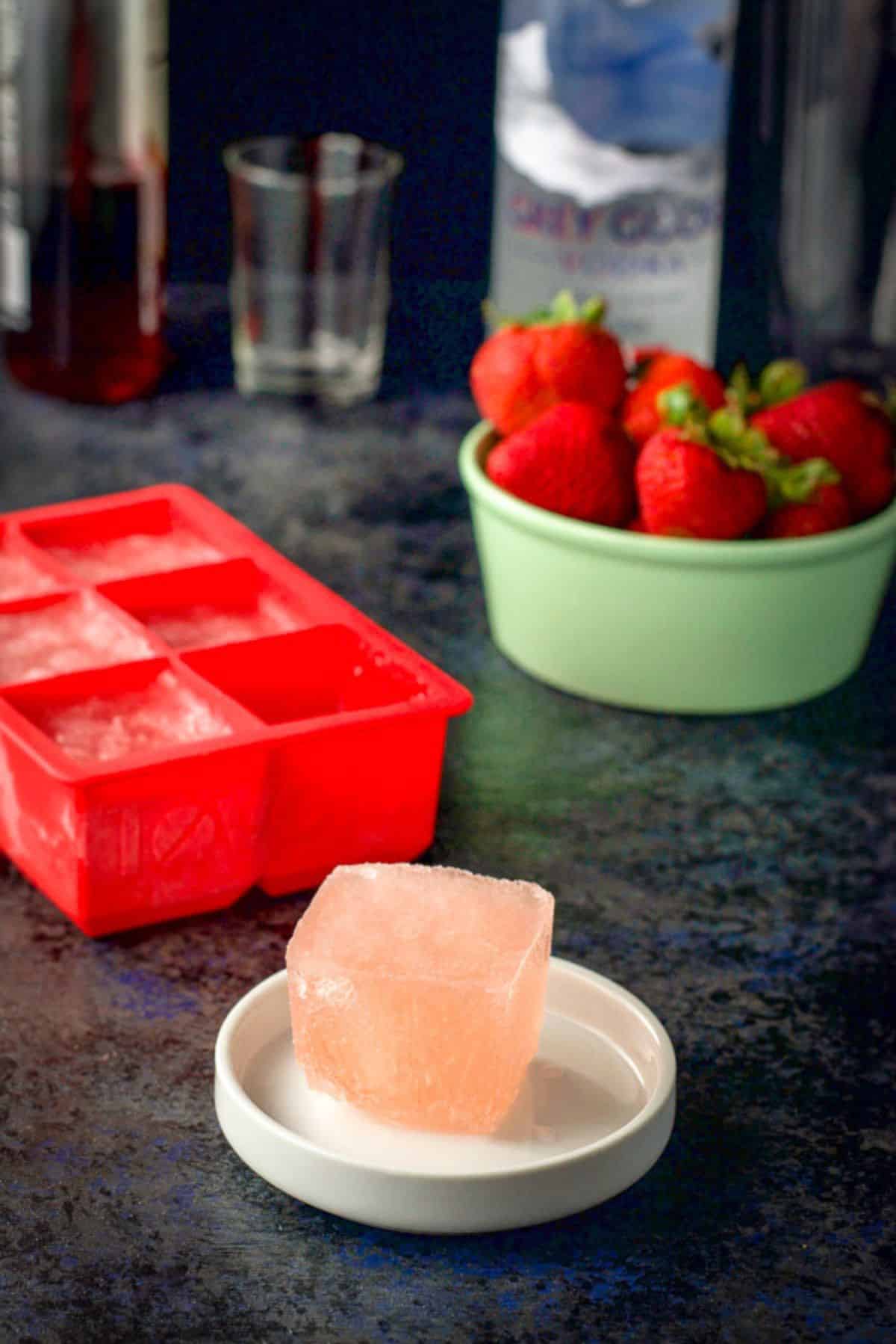 Frose ice cubes, strawberries, vodka and grenadine on a table