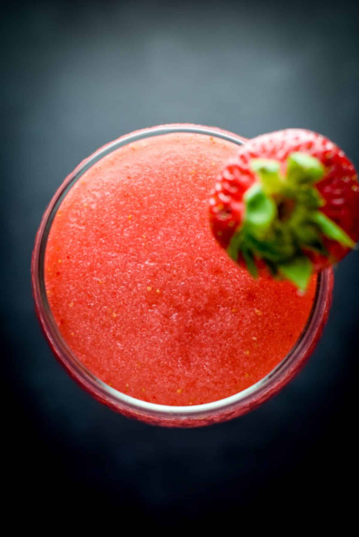 Overhead view of the red frozen cocktail with a strawberry on the rim