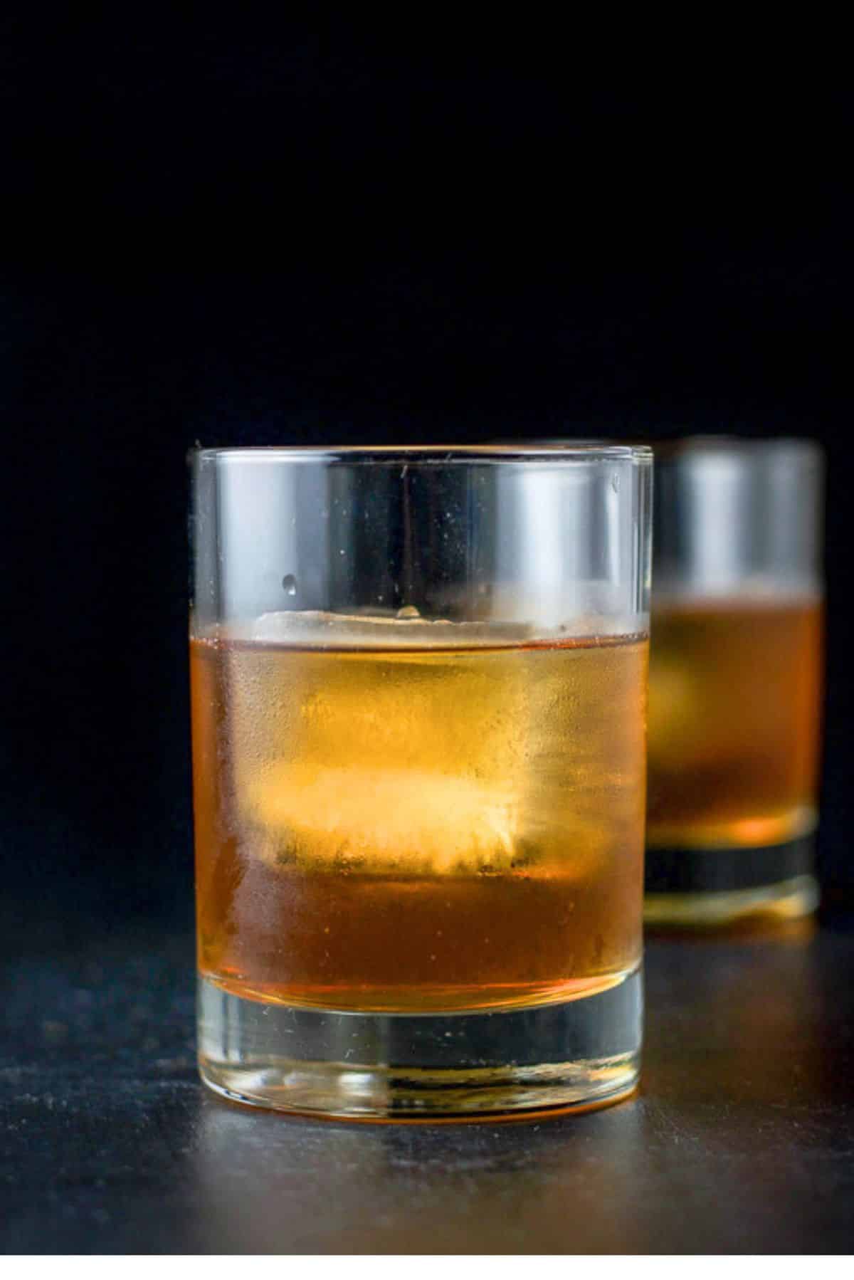 Vertical view of two staggered glasses filled with the amber drink