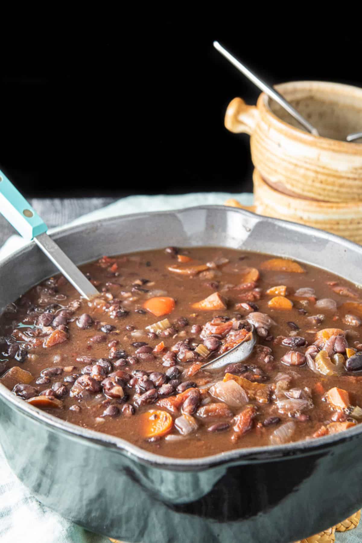 A pan filled with the bean soup with crocks in the background