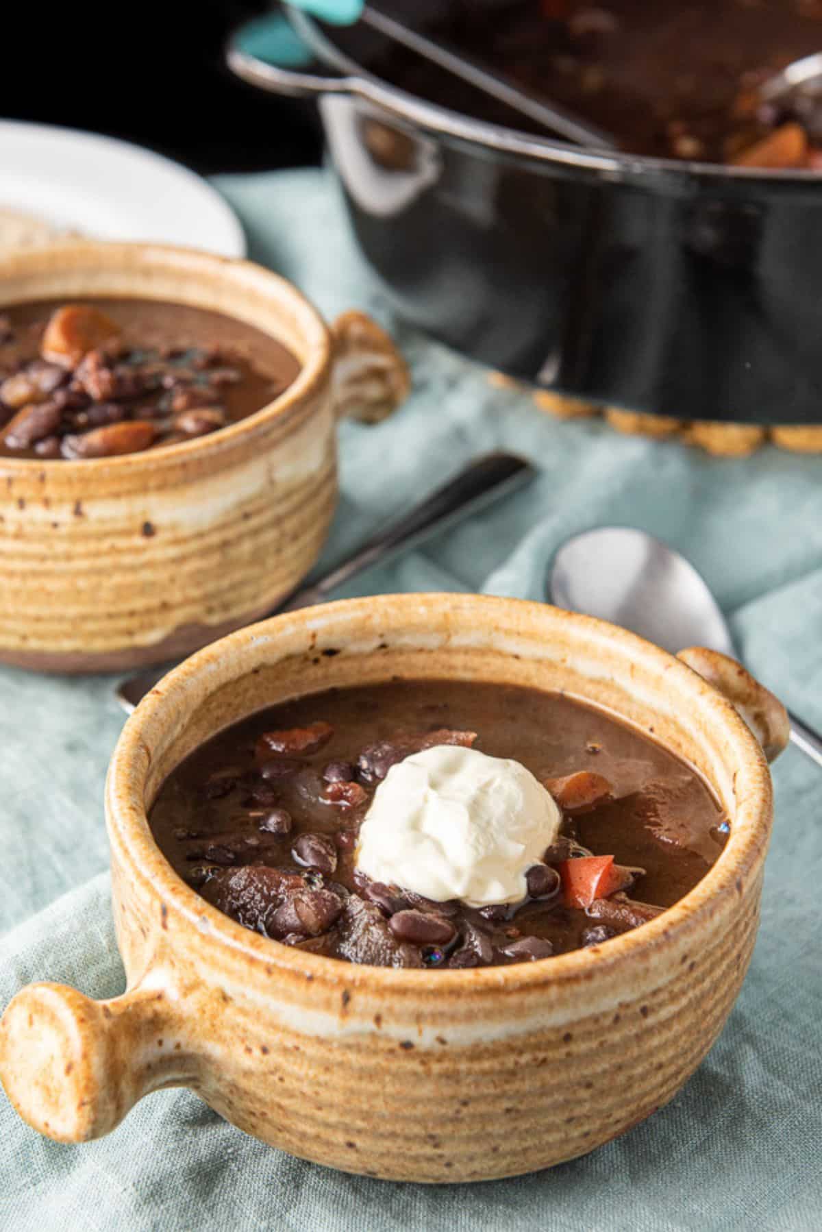Sour cream dolloped on one of the crocks of soup with the pan in the background