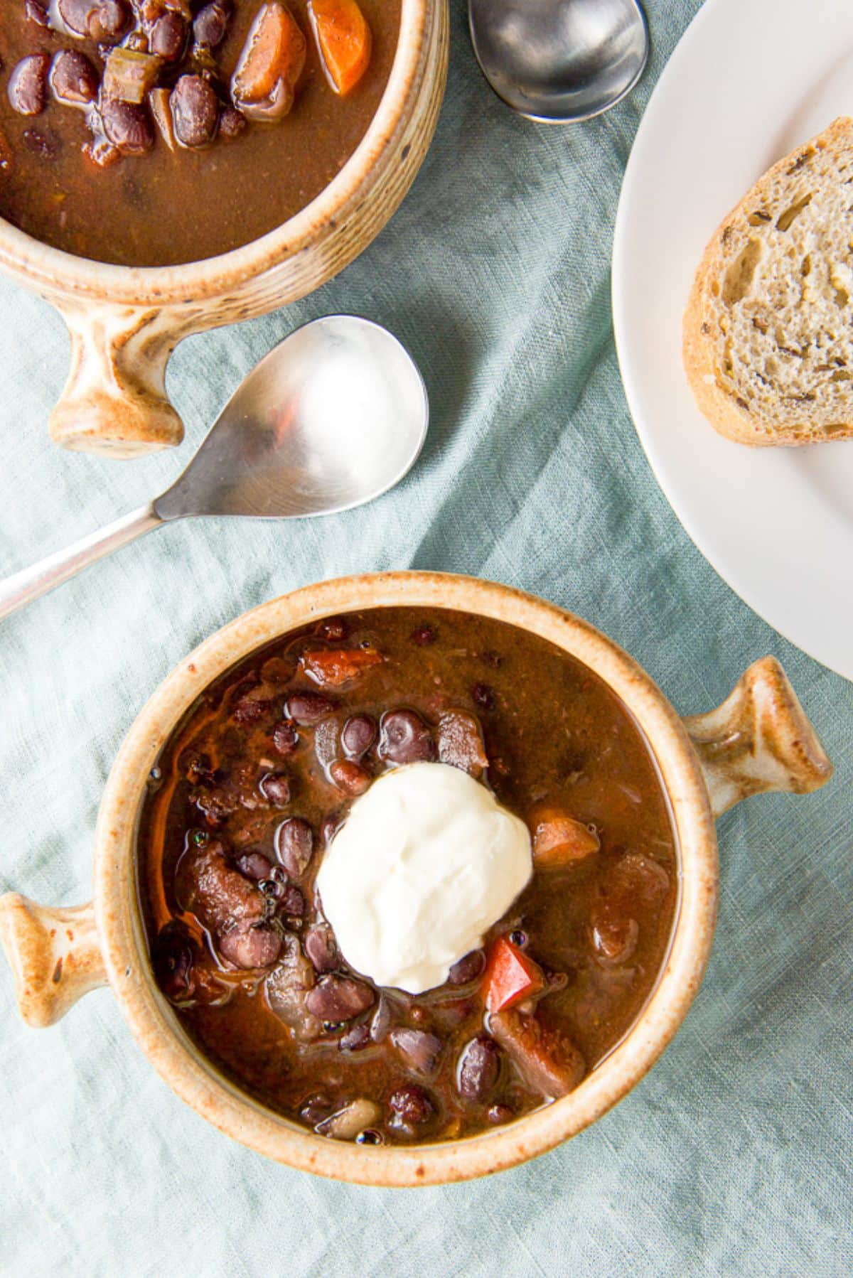 Overhead view two brown crocks of soup, one with sour cream in it