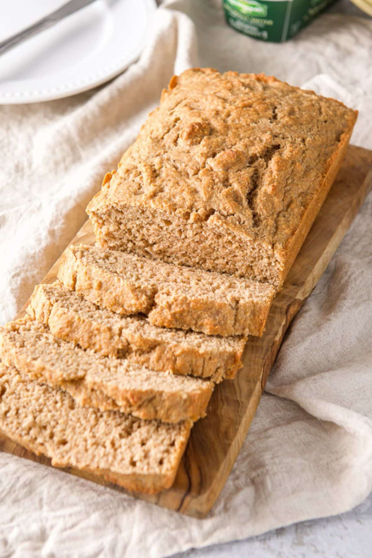 The quick bread sliced on a wooden board with butter in the background