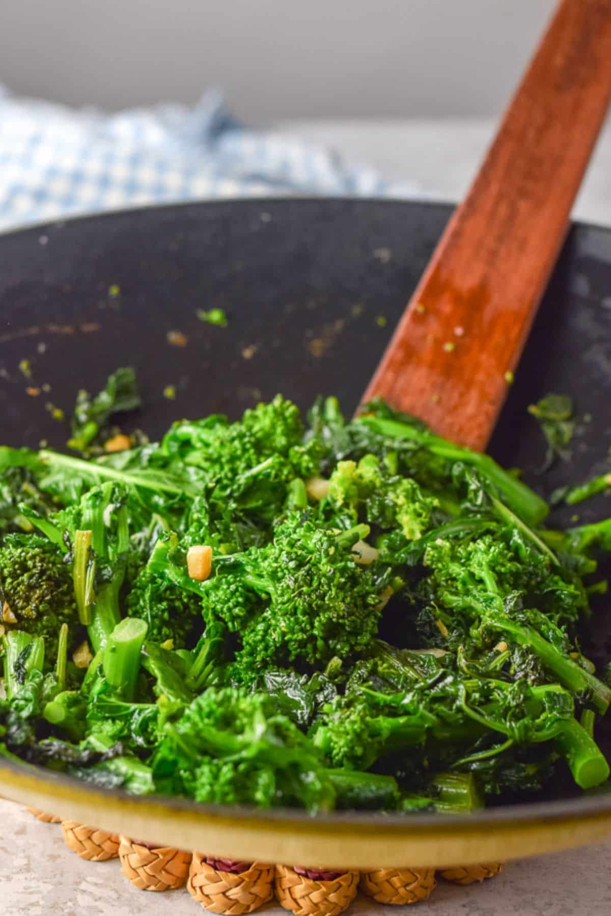 A yellow wok filled with cooked broccoli rabe