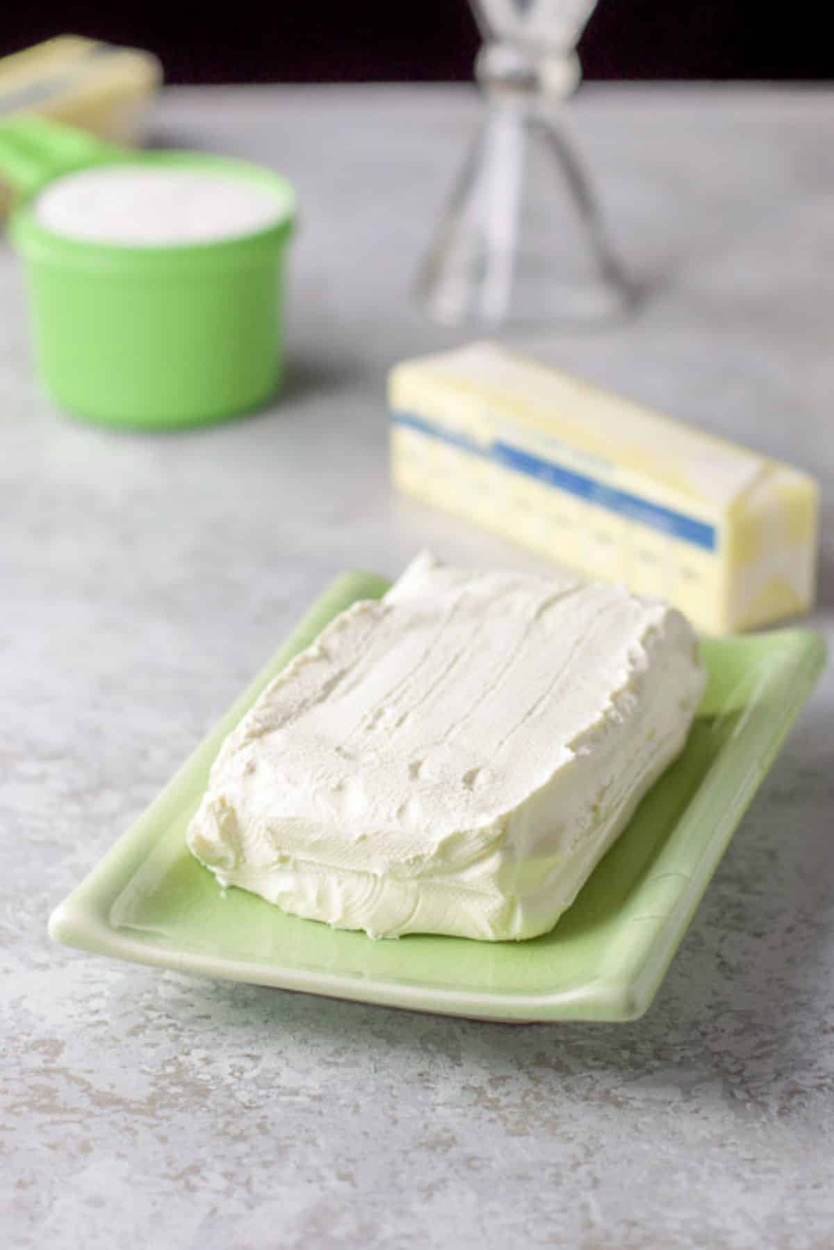 A green rectangle plate with cream cheese on it with butter, sugar, and an egg