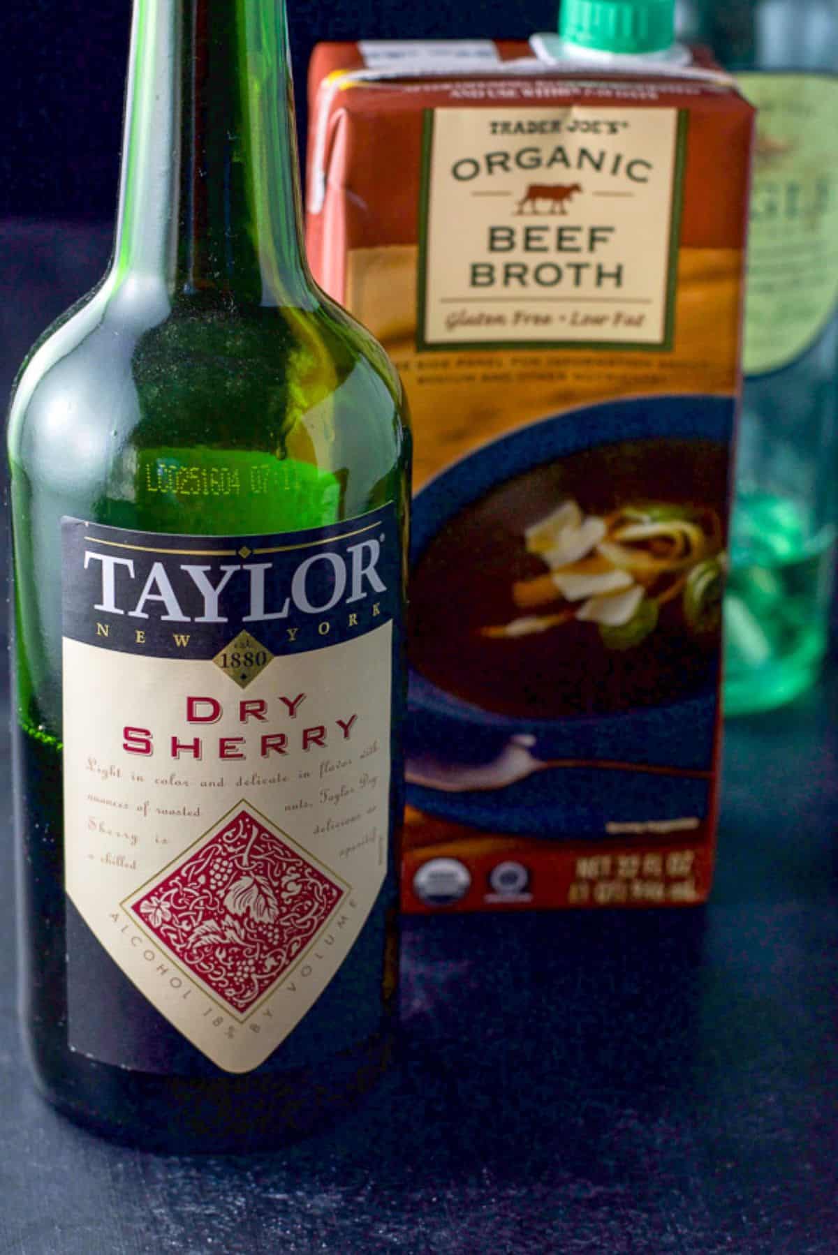 Dry sherry, beef broth and white wine on a black table