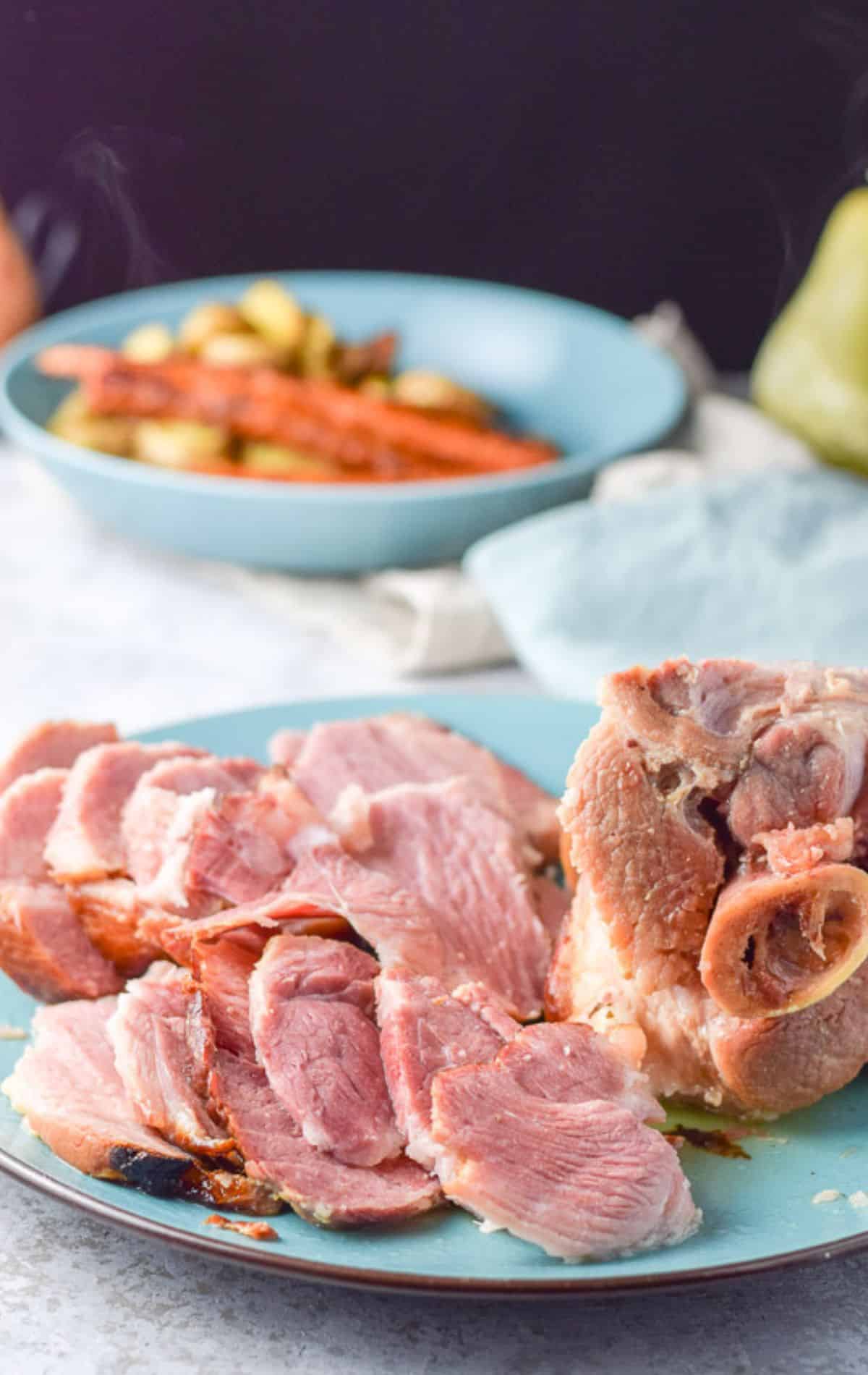 sliced ham shoulder on the plate with some vegetables in the background